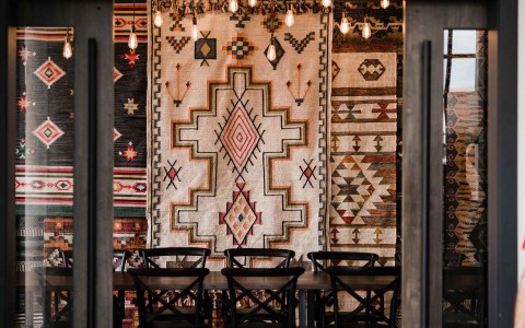 tribal rugs on a wall behind a table