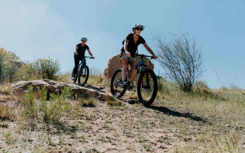 two people riding bikes down slope