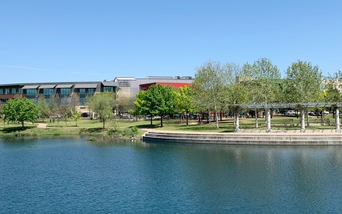 aerial view of a lake, trees and a building around with a clear sky at daytime