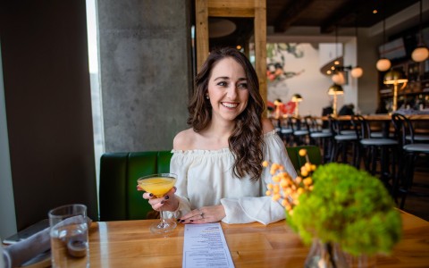 woman sitting at a table having a cocktail