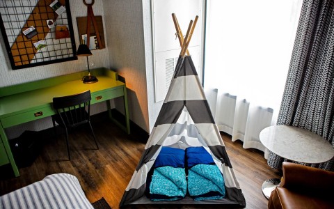 grey and white teepee tent for kids inside a hotel room
