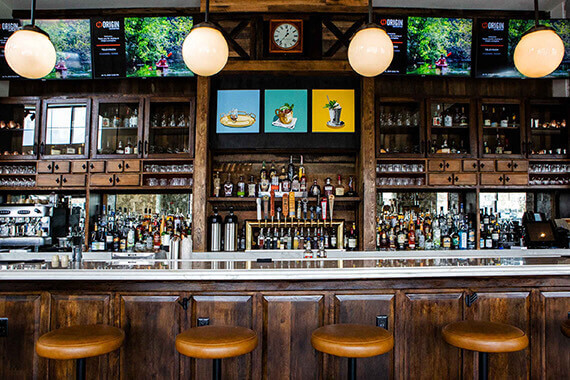 bar stools and tables with wall of liquor bottles