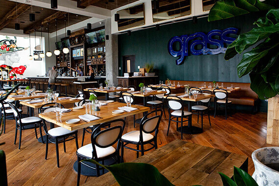 restaurant with multiple seating areas and wall with "Grass" light fixture