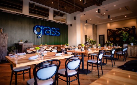 restaurant with multiple seating areas and wall with "Grass" light fixture