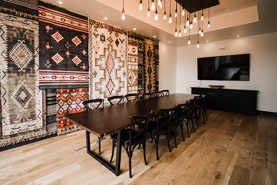 long wooden conference table with tribal patterned rugs in the back wall