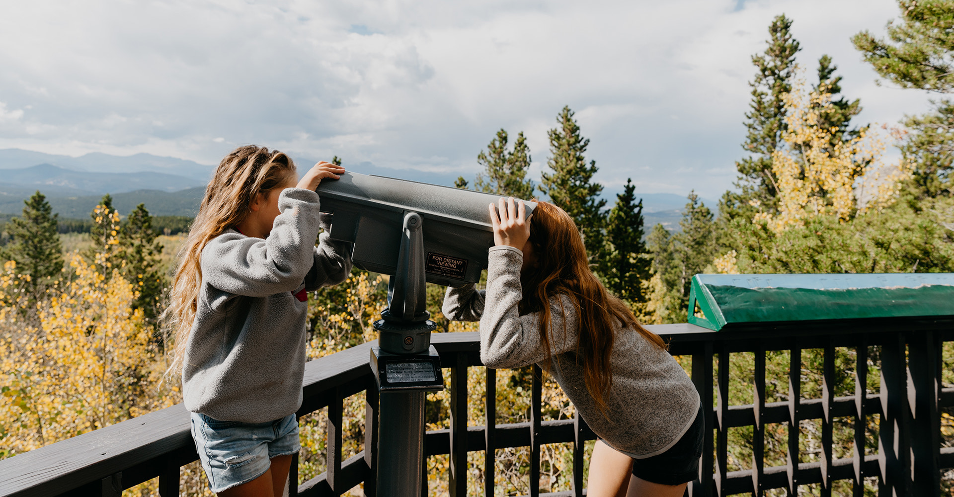 two friends looking through a telescope outside