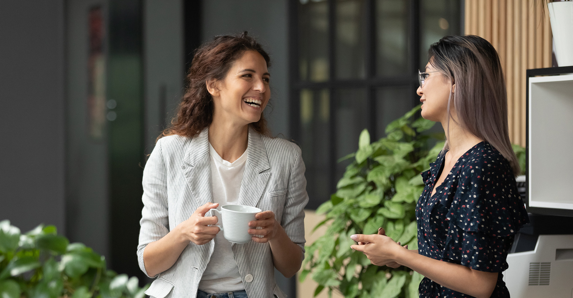 two women in business clothes outside having coffee