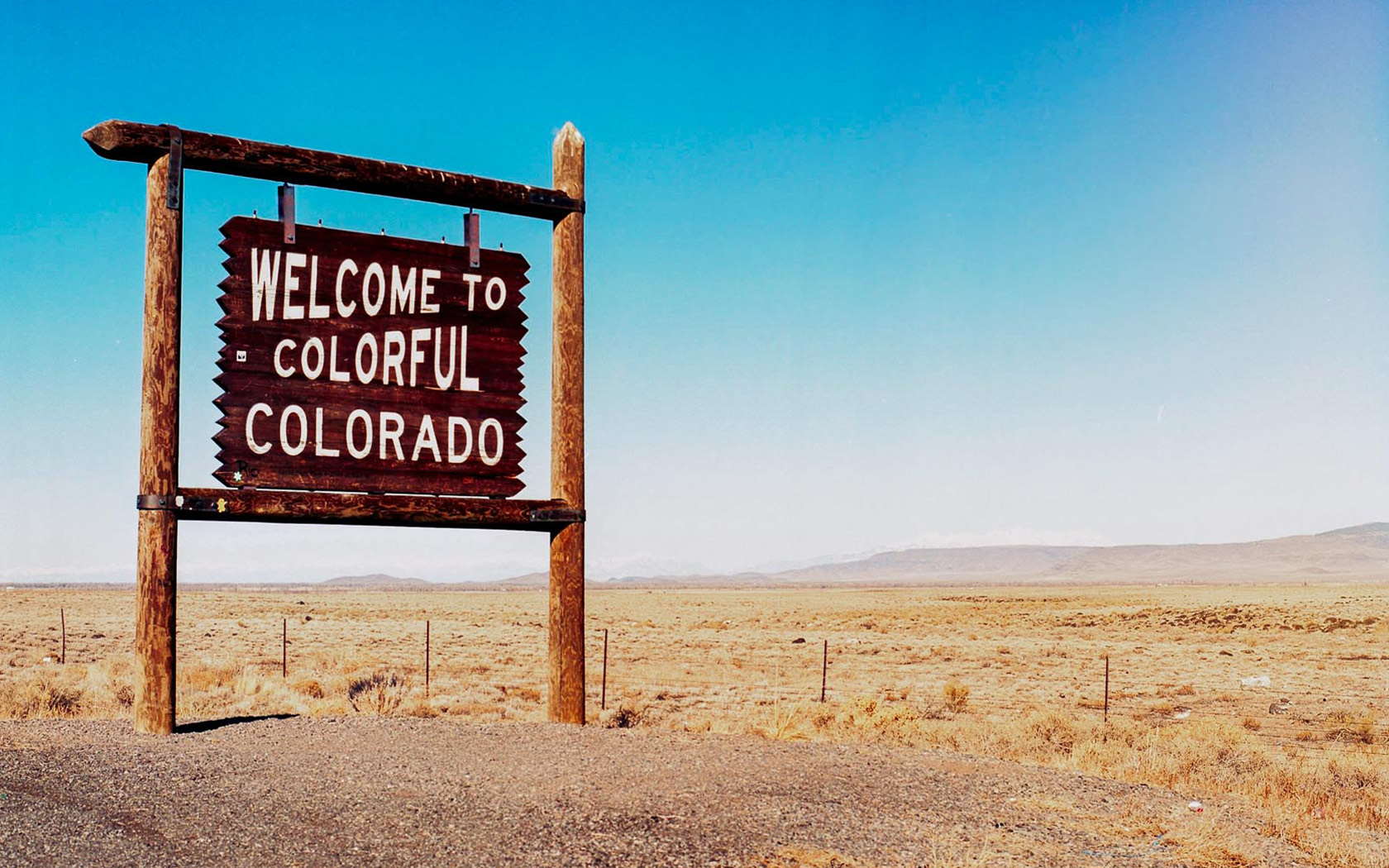 sign in the dessert that says Welcome to Colorful Colorado