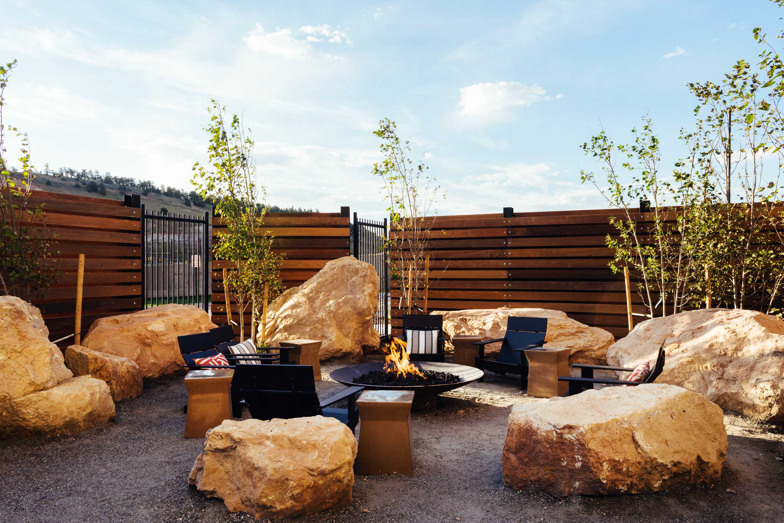 outside firepit surrounded by black patio chairs and large rocks