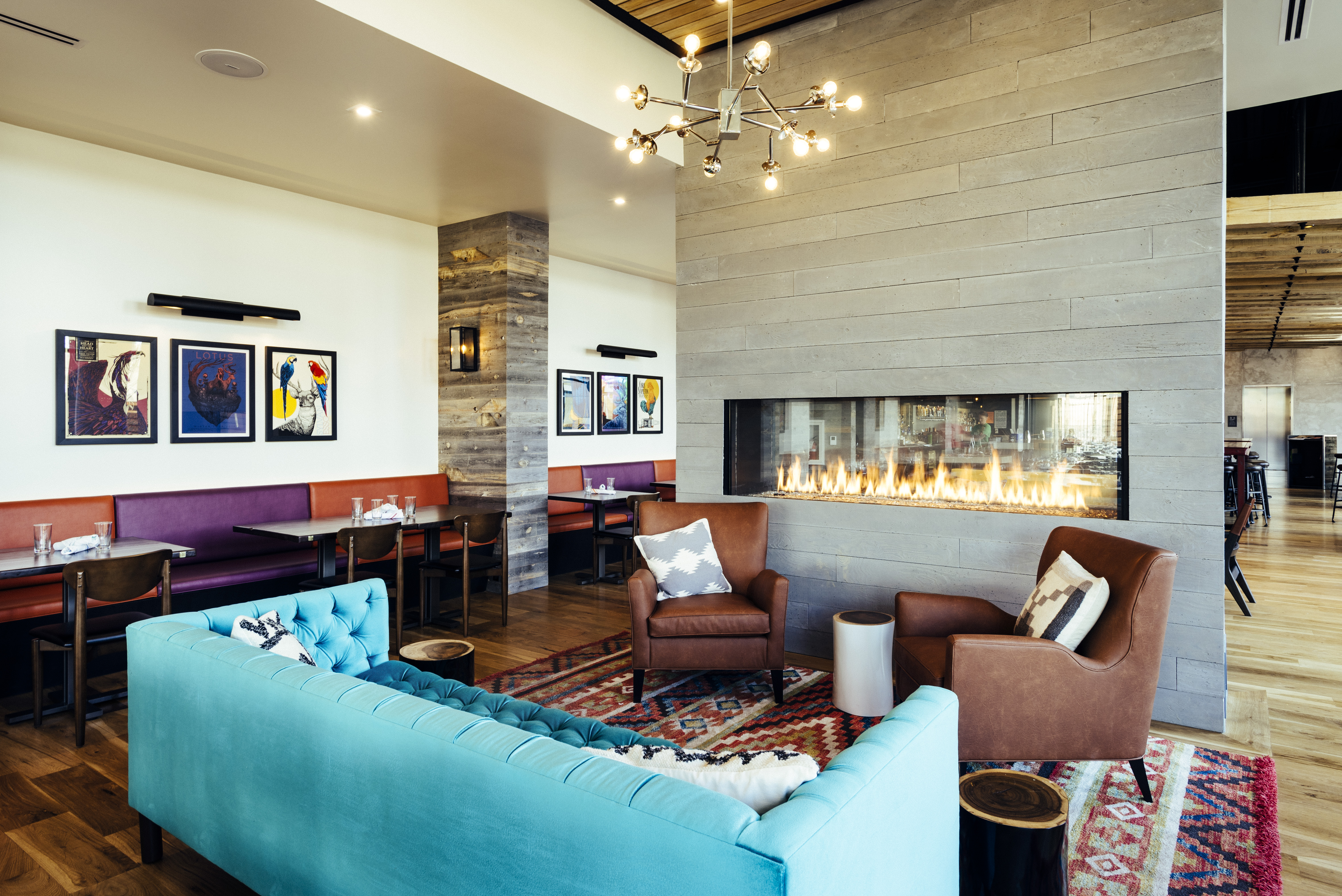 large open space with living room couches of different colors and a fireplace surrounded by glass