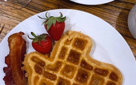 close up of a waffle shaped like texas with bacon and strawberries 