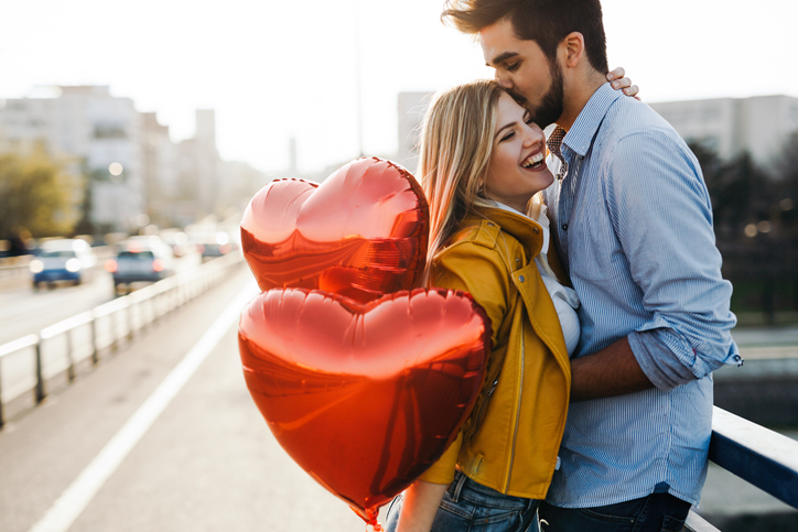 couple laughing holding heart shaped balloons