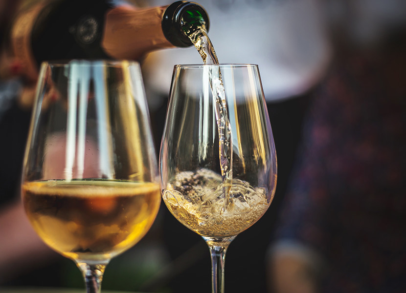 pouring white wine in two wine glasses