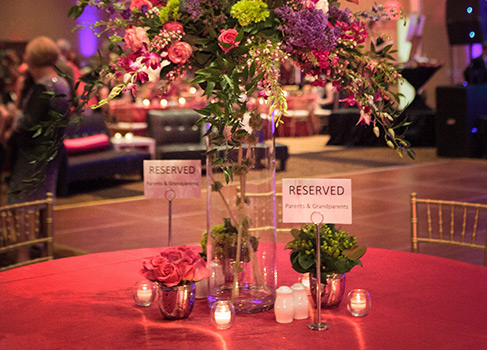 a table set up with a pink table cloth, flowers in vases and signs that say reserved