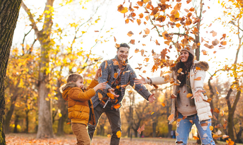 family playing in autumn leaves