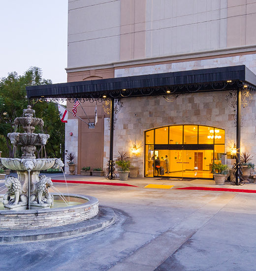 Closeup view of Hilton hotel entrance at nighttime and a medium sized water source at the front