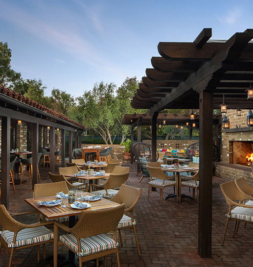 Empty modish outdoor restaurant with setup tables and a fireplace wall in a warm atmosphere 