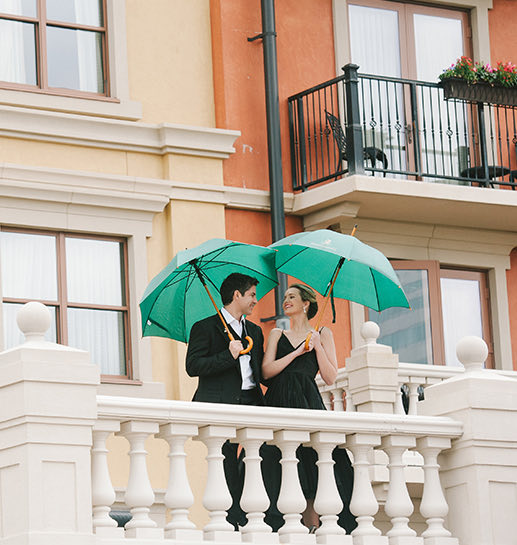 Well black dressed couple with a green umbrellas looking at each other in a balcony