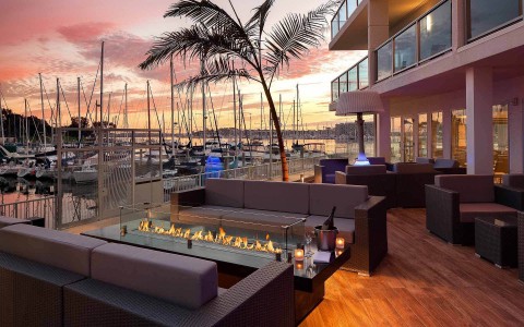 Terrace at sunset with fire pit and sitting area and marina on the background