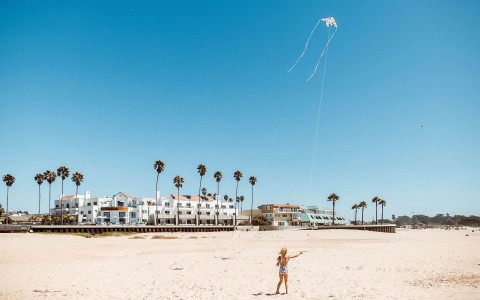 Little girl flying a kite a the beach on a sunny day
