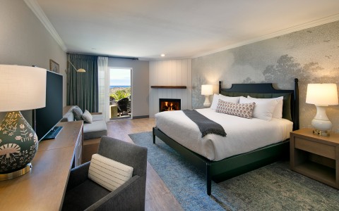 a guest room with a king bed and fireplace