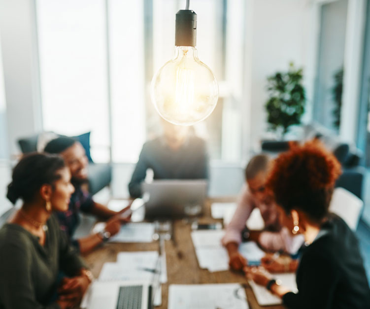people around a table having a meeting with focus on modern lightbulb
