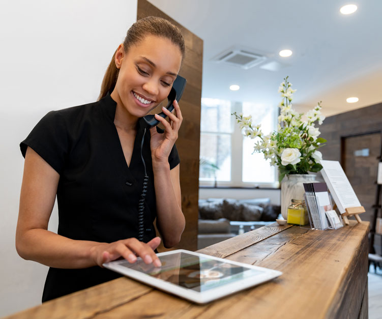 woman at front desk on phone and ipad