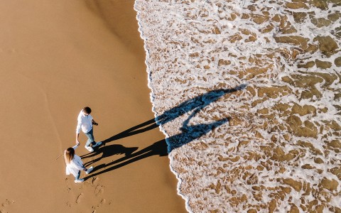 Overhead image of couple walking towards ocean