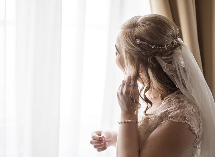 woman putting earrings on before her wedding