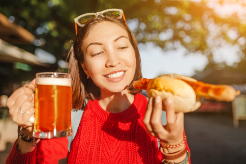 traveler woman drinks mug of beer with hotdog