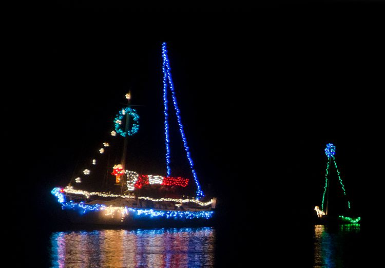 Sail boats on water lit up with Christmas lights