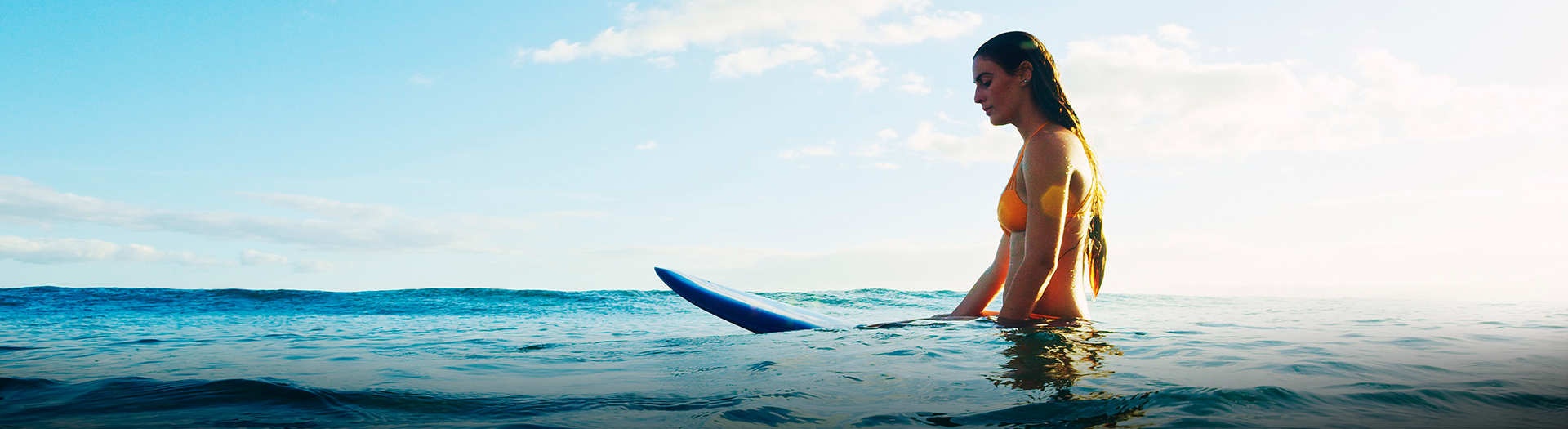 woman swimming on the ocean with a surfboard