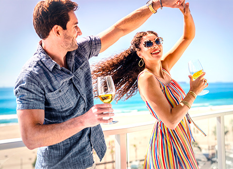 woman and man dancing in front of the beach with glasses