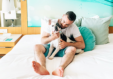 man laying in bed with a french bulldog in his lap