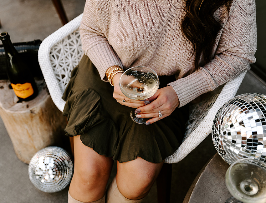 girl holding champagne with disco balls NYE