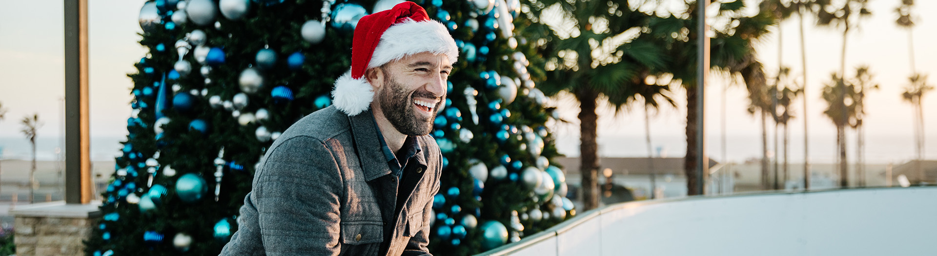 man with santa hat and christmas holiday tree