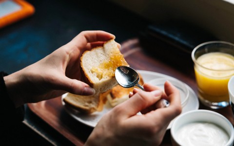 close up of a person spreading jam on a piece of toast