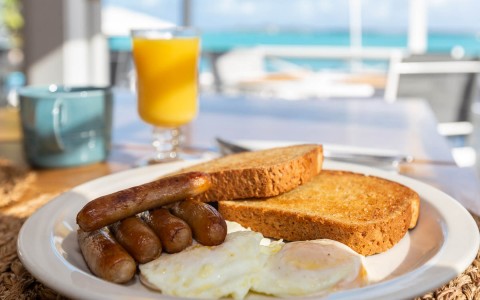 close up of a plated breakfast with eggs, sausage and toast