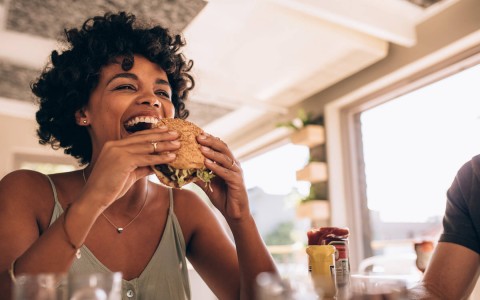 woman taking a bite from a juicy hamburger