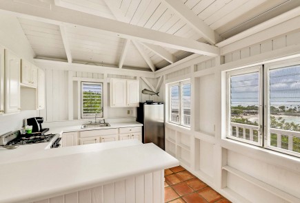 general view of a cottage kitchen with fridge, stove and windows around with ocean view