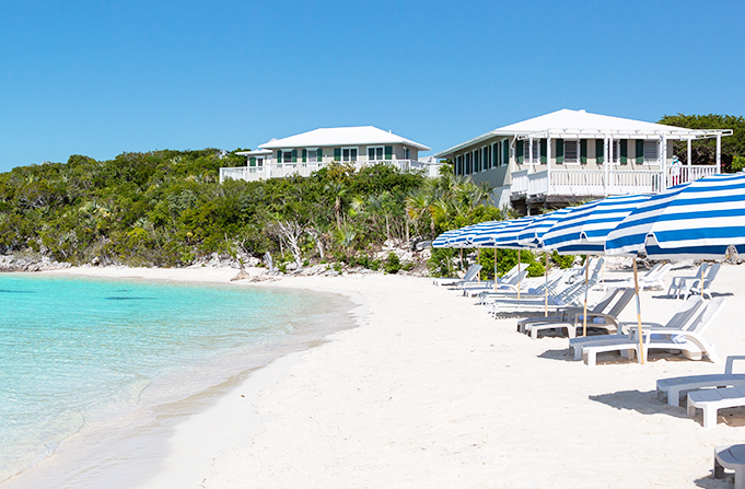 shore of the beach with crystal clear water, and beach chairs and umbrellas in front