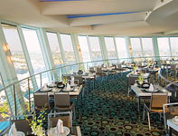 Restaurant seating area at the top of hotel building with panoramic view of city through window panels