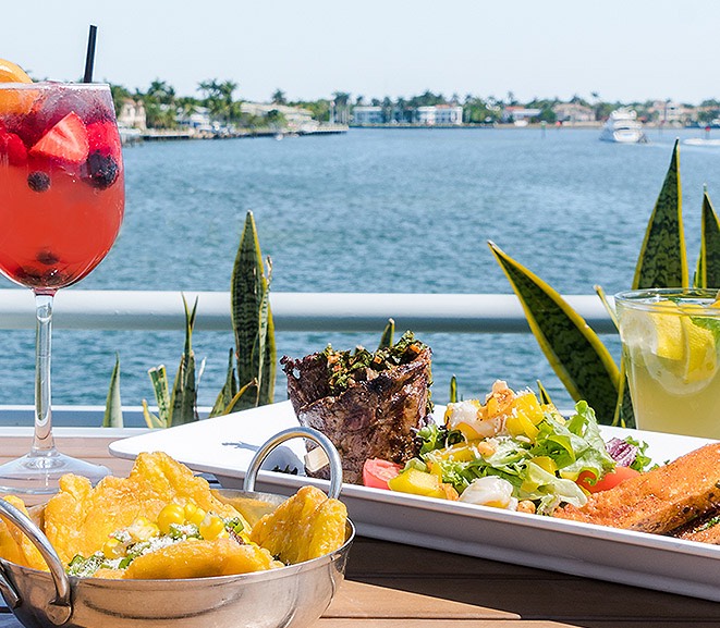 Food on metal tray next to fruity cocktail