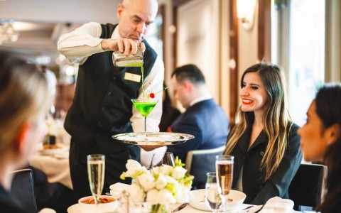 Waiter pouring green drink into martini glass