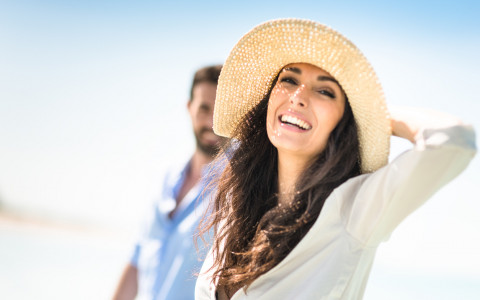 woman smiling at beach with hat