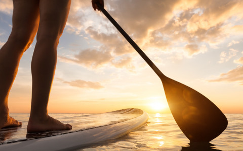 guy or girl paddleboarding into the sunset