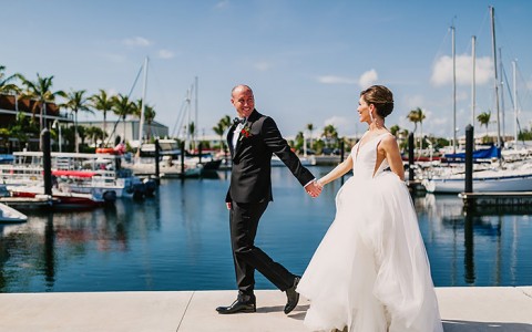 bride and groom holding hands with water and boats in the background