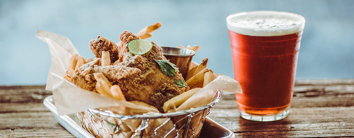 view of fried chicken and chips with a glass of beer by the side