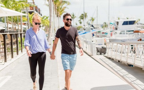 couple wearing sunglasses laughing while they are walking in the street at daytime