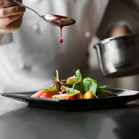 chef plating a meal with sauce